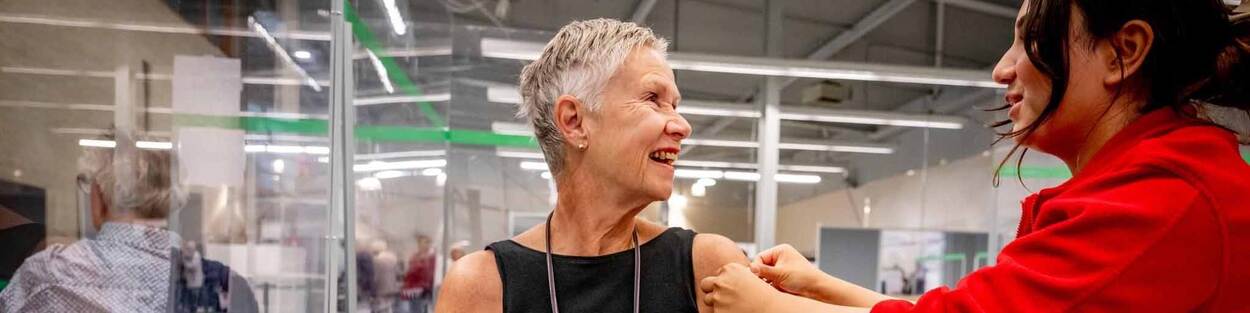 Verpleegkundige doet pleister op arm van vrouw na coronavaccinatie